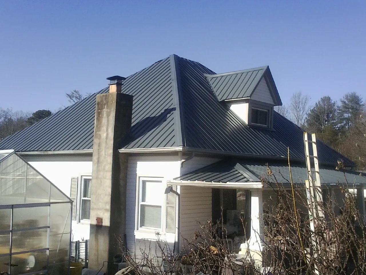 Dark blue standing seam metal roof on a white farmhouse with dormer — Slate & Tile Roof Repair by Roofing Brothers in Mossyrock