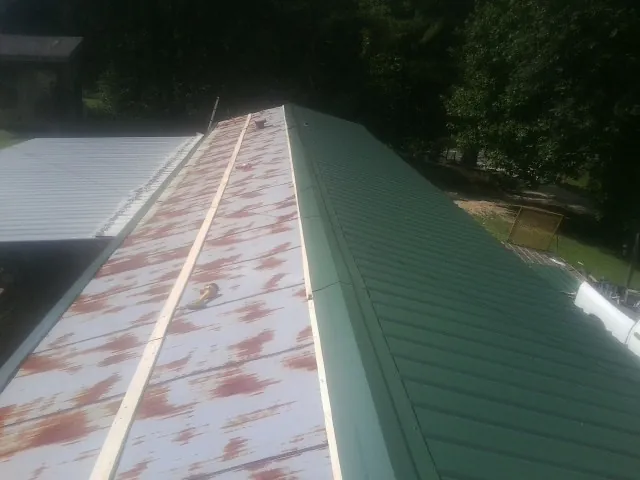 Old rusted panels beside newly installed green metal roofing — Wind Damage Roof Repair by Roofing Brothers in Mossyrock