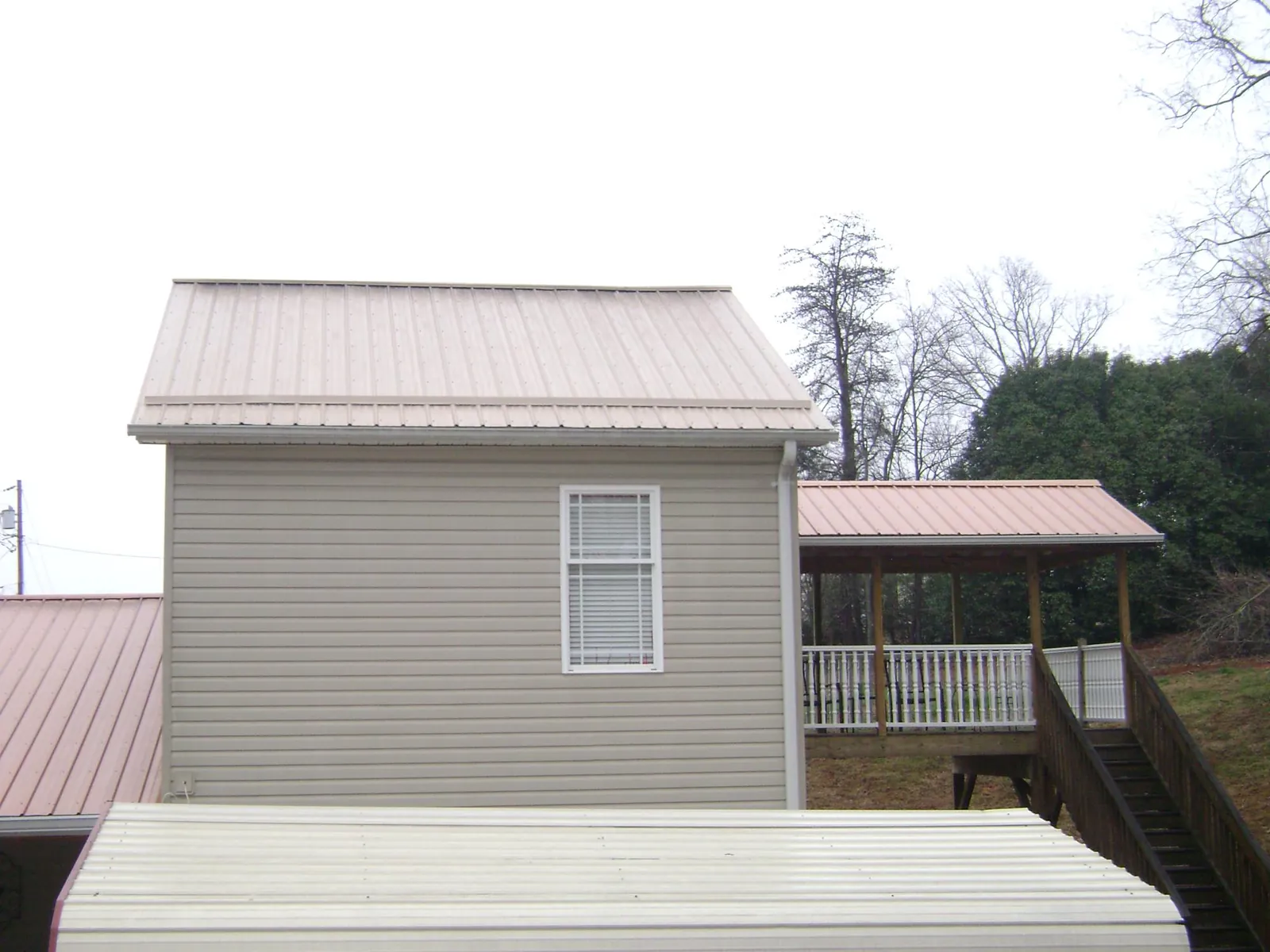 Tan metal roofs on a two story addition and attached porch, from a Roof Replacement job in Mossyrock