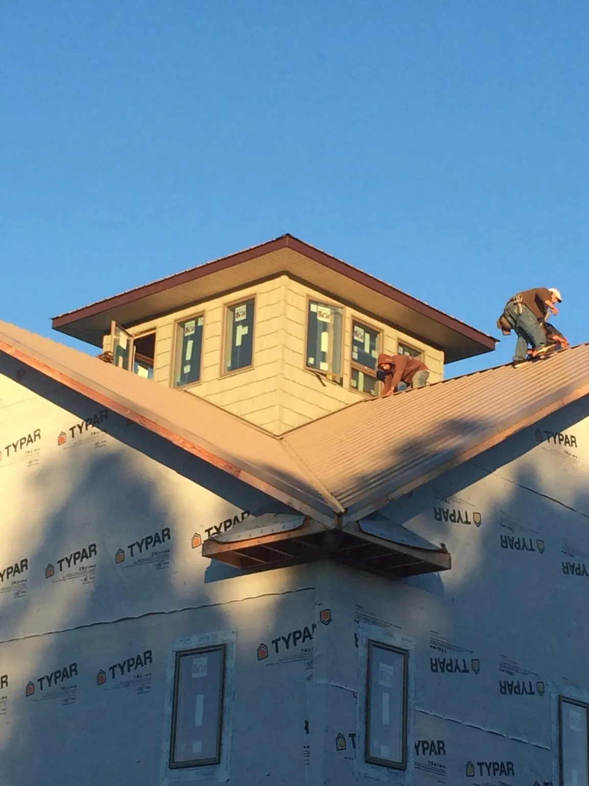 Roofers working around a rooftop cupola on a new metal roof at sunset — Roof Waterproofing in Mossyrock by Roofing Brothers